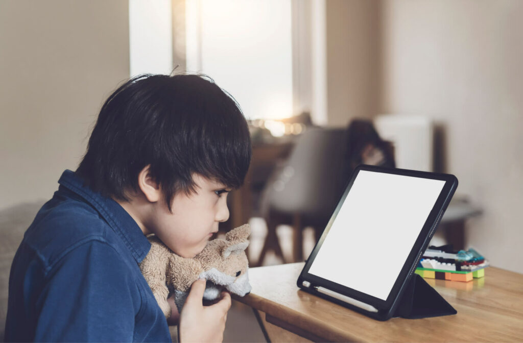 A nearsighted boy child  sitting in front of his digital tablet and looking closely at the screen.