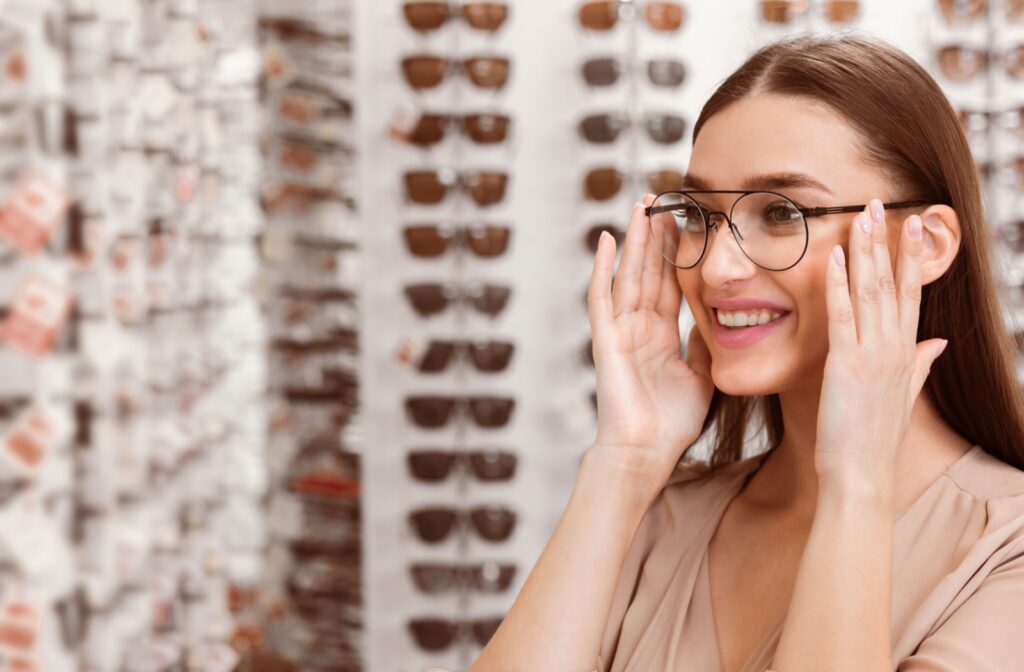 A person smiles as they try on eyeglasses at an optical store.